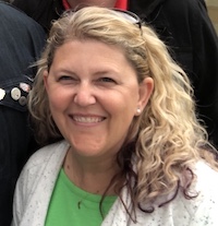 Photo of Allison Carr, a woman with blonde curly hair, wearing a green shirt and white jacket